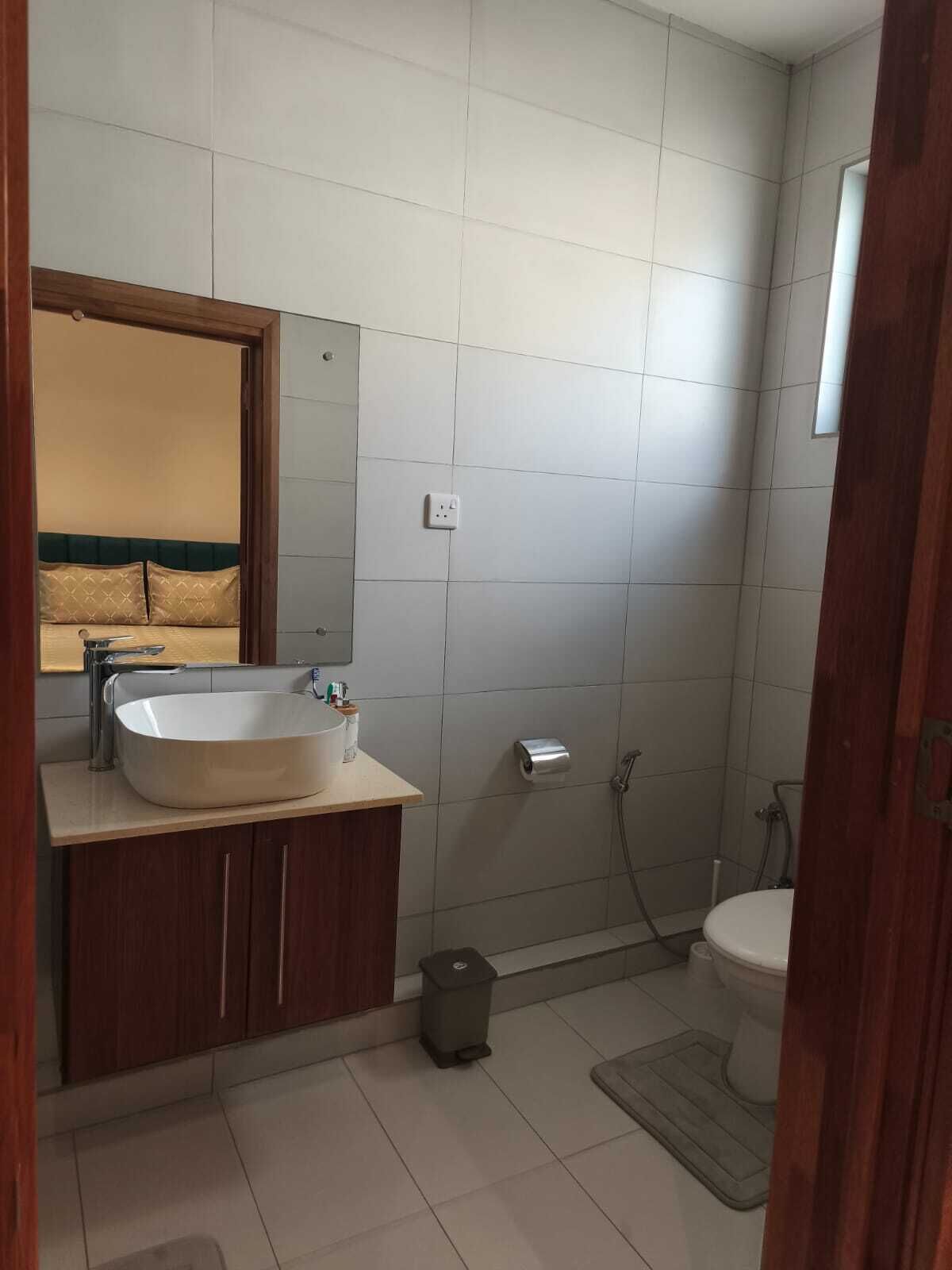 A bathroom with a sink, mirror, toilet, and shower.