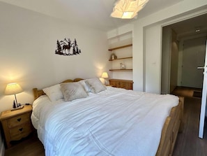 A bedroom with a large bed, bedside tables, a wall decoration, and a door leading to another room. - 1st floor, terrace, tv, 82m², Serre Chevalier (SERRE CHEVALIER)