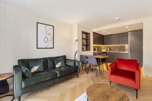 A modern living room with a dark green sofa, a red armchair, and a wooden coffee table. - The Pullman Suite - near train station (York)