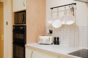 A kitchen with a toaster, oven, and hanging pots. - The Gallery House - Minster Views & Sleeps up to 8 (York)
