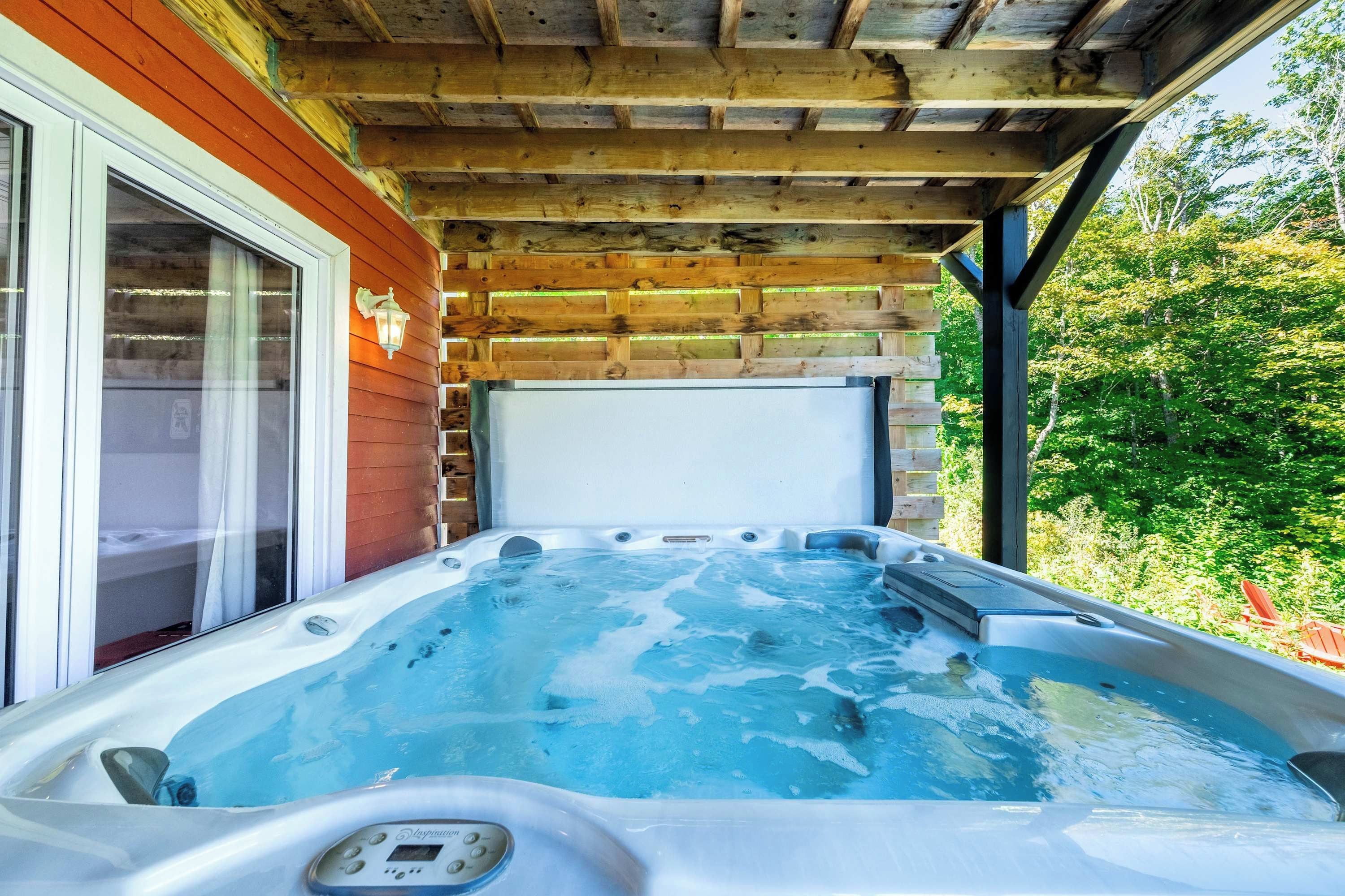 Ein Whirlpool unter einer Hollaube, mit einer Holzwand und einem Fenster zur Linken.