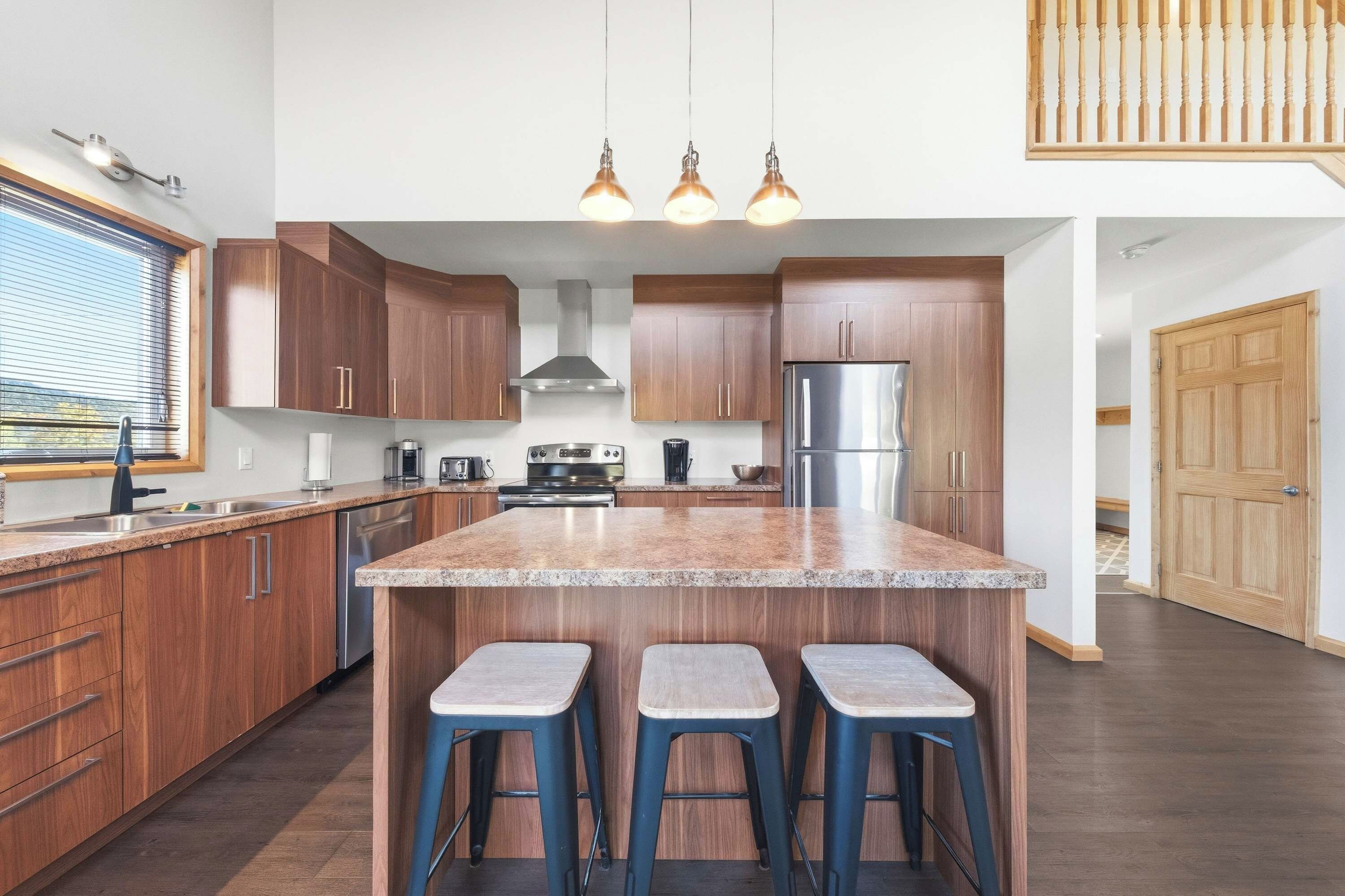 A modern kitchen with wooden cabinets, a stainless steel refrigerator, and a granite countertop.