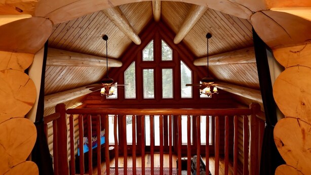 Een houten interieur met een schuine kap, een houten leuning en uitzicht op de omgeving.