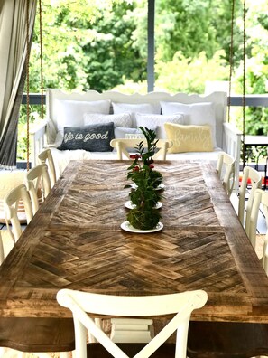 A wooden dining table with chairs, a hanging plant centerpiece, and a white sofa with cushions in the background. - Cozy 3-Level Chattanooga Retreat with Relaxing Outdoor Spaces (Chattanooga)