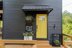 A building with a dark exterior, a yellow door, and a welcome sign. - Cozy 3-Level Chattanooga Retreat with Relaxing Outdoor Spaces (Chattanooga)