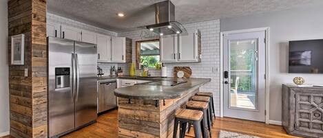 A modern kitchen with a central island, stainless steel appliances, and a rustic wooden accent wall.
