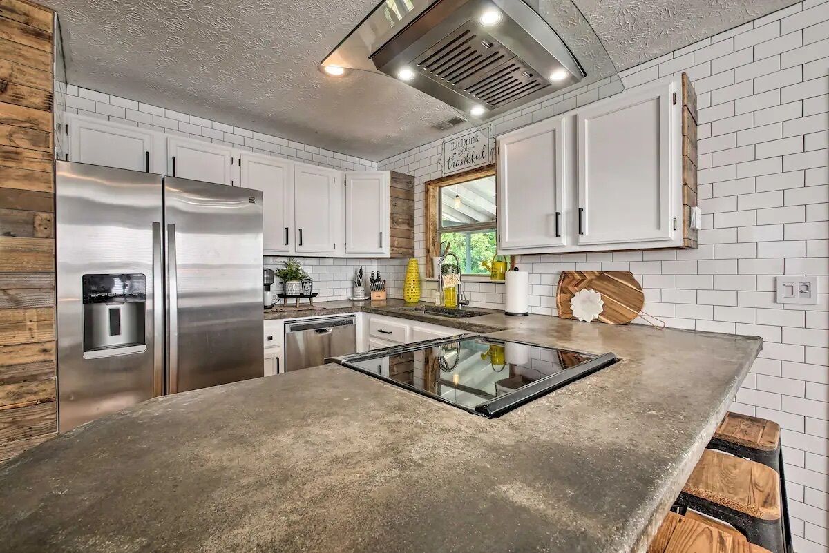 A kitchen with white cabinets, a stainless steel refrigerator, a built-in oven, and a wooden accent wall.