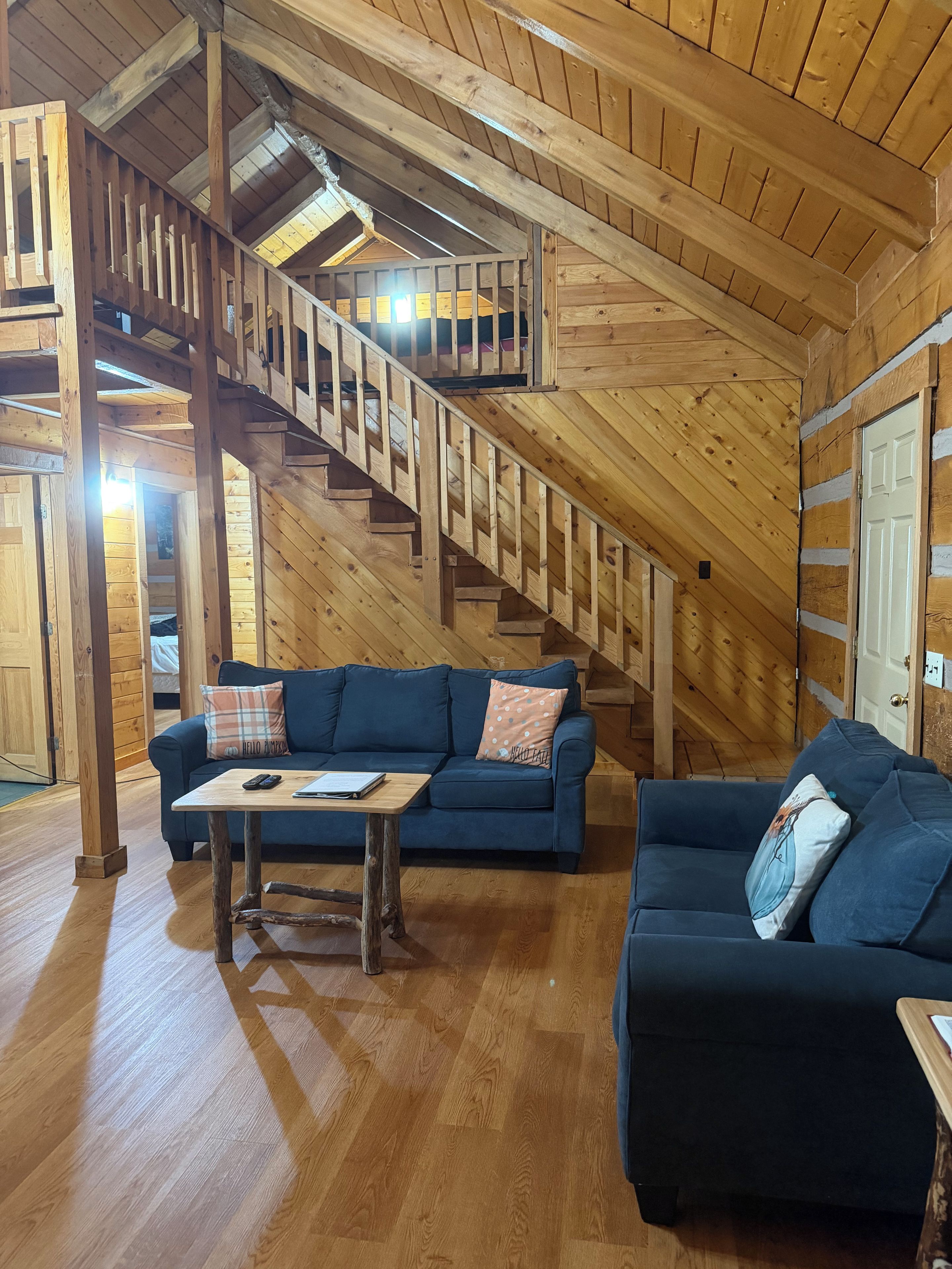 Ein Holzinnenraum mit einer Treppe, zwei Sofas, einem Tisch und einer Tür.