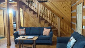 Ein Holzinnenraum mit einer Treppe, zwei Sofas, einem Tisch und einer Tür.