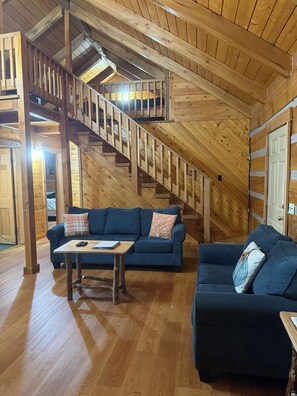 Ein Holzinnenraum mit einer Treppe, zwei Sofas, einem Tisch und einer Tür.