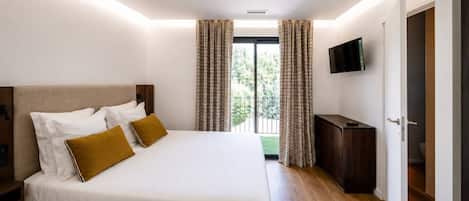 Una habitación de hotel con una cama grande, un televisor de pantalla plana montado en la pared y vistas al exterior por la ventana.