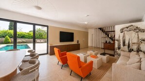 Un salon moderne avec vue sur la piscine, un téléviseur à écran plat et un escalier menant à un niveau supérieur.