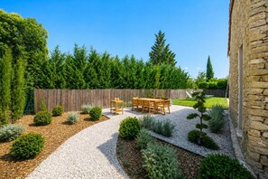 A garden with a gravel path, wooden furniture, and various shrubs. - La Bâtisse - Piscine et jardin - Luberon (Gordes)
