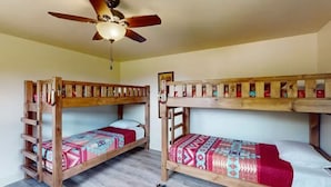 Ein Zimmer mit zwei Etagenbetten, einem Deckenventilator und einer Holzleiter.