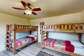 Ein Zimmer mit zwei Etagenbetten, einem Deckenventilator und einer Holzleiter.