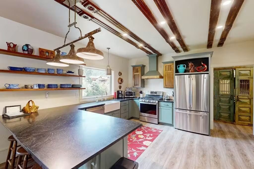 A modern kitchen with a central island, stainless steel appliances, and wooden beams on the ceiling.
