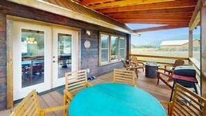 Ein überdachter Außenbereich mit Holzdeck, einem runden Tisch und mehreren Stühlen.