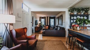 Een gezellige woonkamer met een leren fauteuil, een bank, een houten salontafel en een open haard.