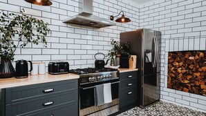Ett modernt kök med ett kylskåp i rostfritt stål, en gasspis och en svart brödrost.