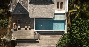 Ein Luftbild eines modernen Resorts mit Schwimmbad, Holzterrasse und Liegebereich.
