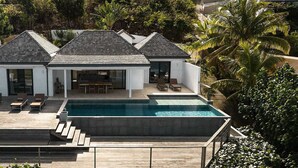 Moderni talo, jossa on uima-allas, ulkotila oleskelua varten ja näkymä ympäröivään vehreään maisemaan.