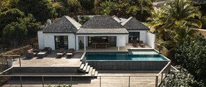 Ein modernes Haus mit Schwimmbad, Sitzgelegenheit im Freien und Blick auf die umliegende Grünfläche.