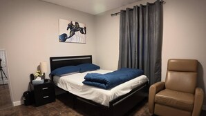 Une chambre à coucher avec un lit, une chaise, une table de chevet avec une lampe et un tableau au mur.