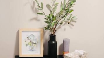 Une table de chevet noire, ornée d’un cadre avec une photo, d’un vase contenant des feuilles vertes et d’une bougie.