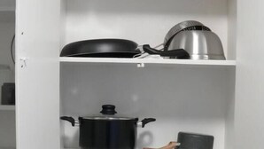 Une cuisine avec des meubles blancs, une cuisinière, une machine à café et une bouteille de liquide vaisselle.