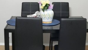 Un coin repas comprenant une table et quatre chaises, un vase avec des fleurs et trois tableaux encadrés accrochés au mur.