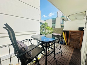 A balcony with a table and chairs, a view of buildings, and a tiled floor. - Cabana Waikiki Walk to Waikiki Beach With Free Parking Sleep for 4! (Honolulu)