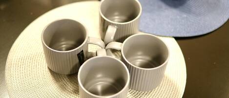 Four white ceramic cups arranged on a textured round mat.