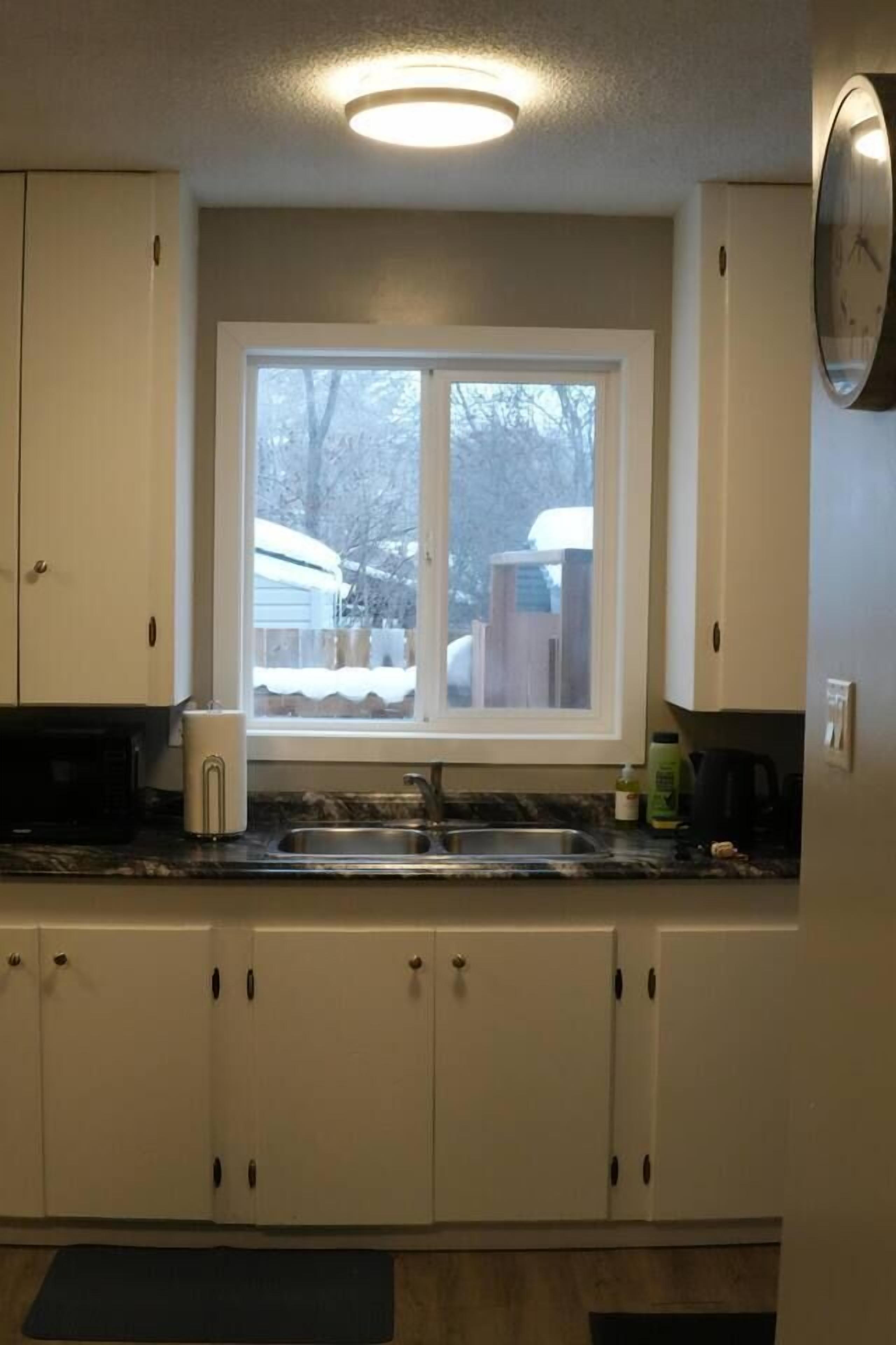 A kitchen with white cabinets, a window, and a sink.