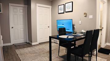 Un espace repas comprenant une table, des chaises, un téléviseur à écran plat et un tapis à motifs.