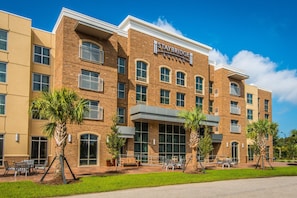 Een Staybridge Suites hotel met een bakstenen gevel, grote ramen en buitenzitplaatsen.
