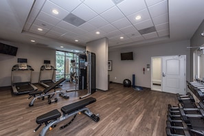 Een sportschool met loopbanden, gewichtbanken en fitnessapparatuur.
