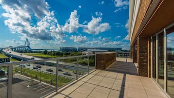 A balcony with a view of a highway and bridge, a parking lot, and a building with large windows.
