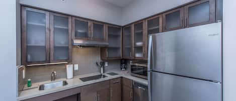 A modern kitchen with stainless steel appliances, wooden cabinets, and a built-in oven.