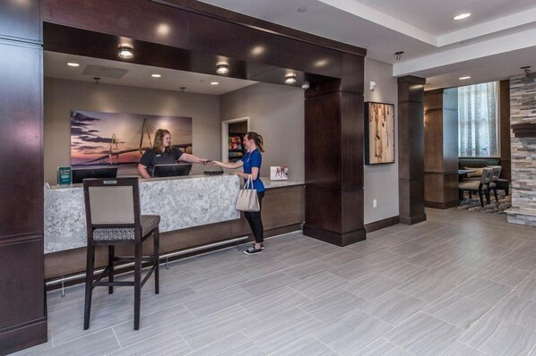 A reception area with a marble counter, a receptionist, and a guest.