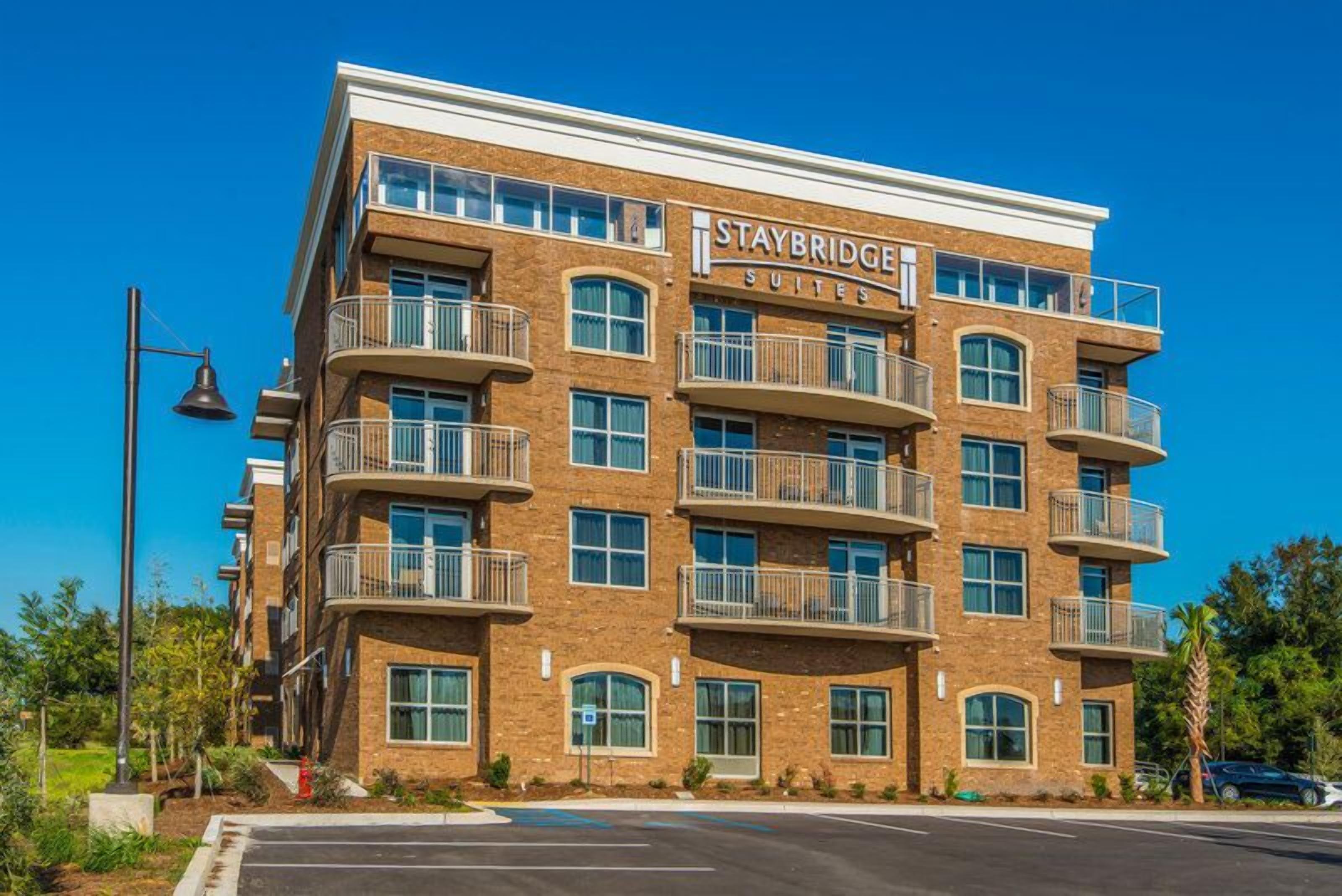En Staybridge Suites bygning med flere balkoner, store vinduer og en murstensfacade.