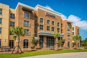 Um hotel Staybridge Suites com fachada de tijolos, janelas amplas e áreas de estar ao ar livre.