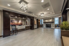 A spacious lobby with a reception desk, a stone fireplace, and a large window. - Free Breakfast | ADA Studio Suite w/ Roll-in Shwr (Mt. Pleasant)