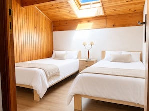 A room with two beds, wooden walls, a skylight, and a nightstand with lamps. - El Balcó de la Cerdanya: Garden, basketball, and tennis. (Palau-de-Cerdagne)