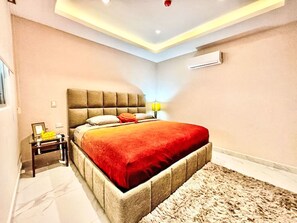 A bedroom with a bed, bedside table, lamp, and an air conditioning unit. - Depto Mazatlán Golden View by Interhome (Mazatlán)