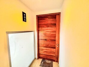 Ein Korridor mit einer Holztür, einer weißen Wand und einem schwarzen Schild mit Nummern.