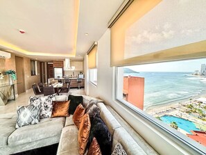 A modern living room with a large window overlooking a coastal view. - Depto Mazatlán Golden View by Interhome (Mazatlán)