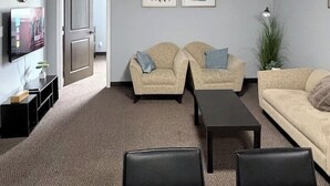A living room with two sofas, a coffee table, and a TV on a stand. - Private 2BR Suite Near Downtown & Hospital (Regina)