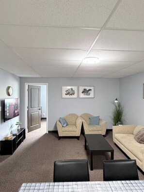 A living room with two sofas, a coffee table, and a TV on a stand. - Private 2BR Suite Near Downtown & Hospital (Regina)
