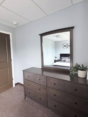 Un dormitorio con un aparador de madera oscura, un espejo grande y una planta en maceta.