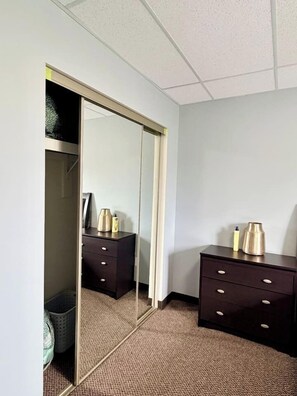 A hotel room with a mirrored closet, two dark wooden nightstands, and a carpeted floor.